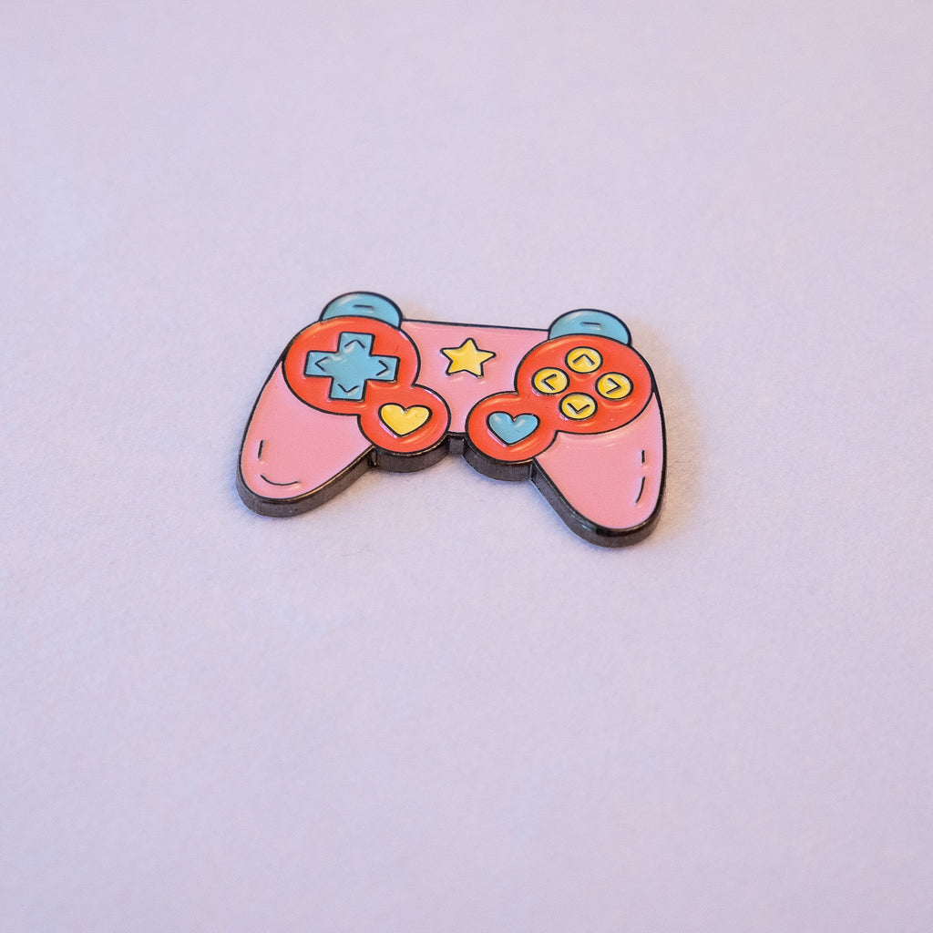 A pink game controller sticker with a mint d-pad, yellow and blue heart thumb sticks, and a star, seen from above.