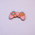 A pink game controller sticker with a mint d-pad, yellow and blue heart thumb sticks, and a star, seen from above.