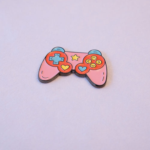 A pink game controller sticker with a mint d-pad, yellow and blue heart thumb sticks, and a star, seen from above.