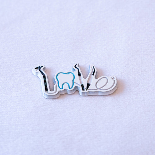 LOVE spelled in dental instruments, a white tooth outlined in blue standing in for the O.