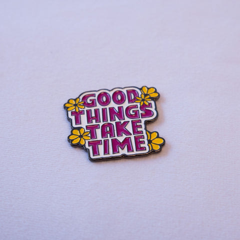 GOOD THINGS TAKE TIME in magenta block caps with four yellow daisies tucked around it.