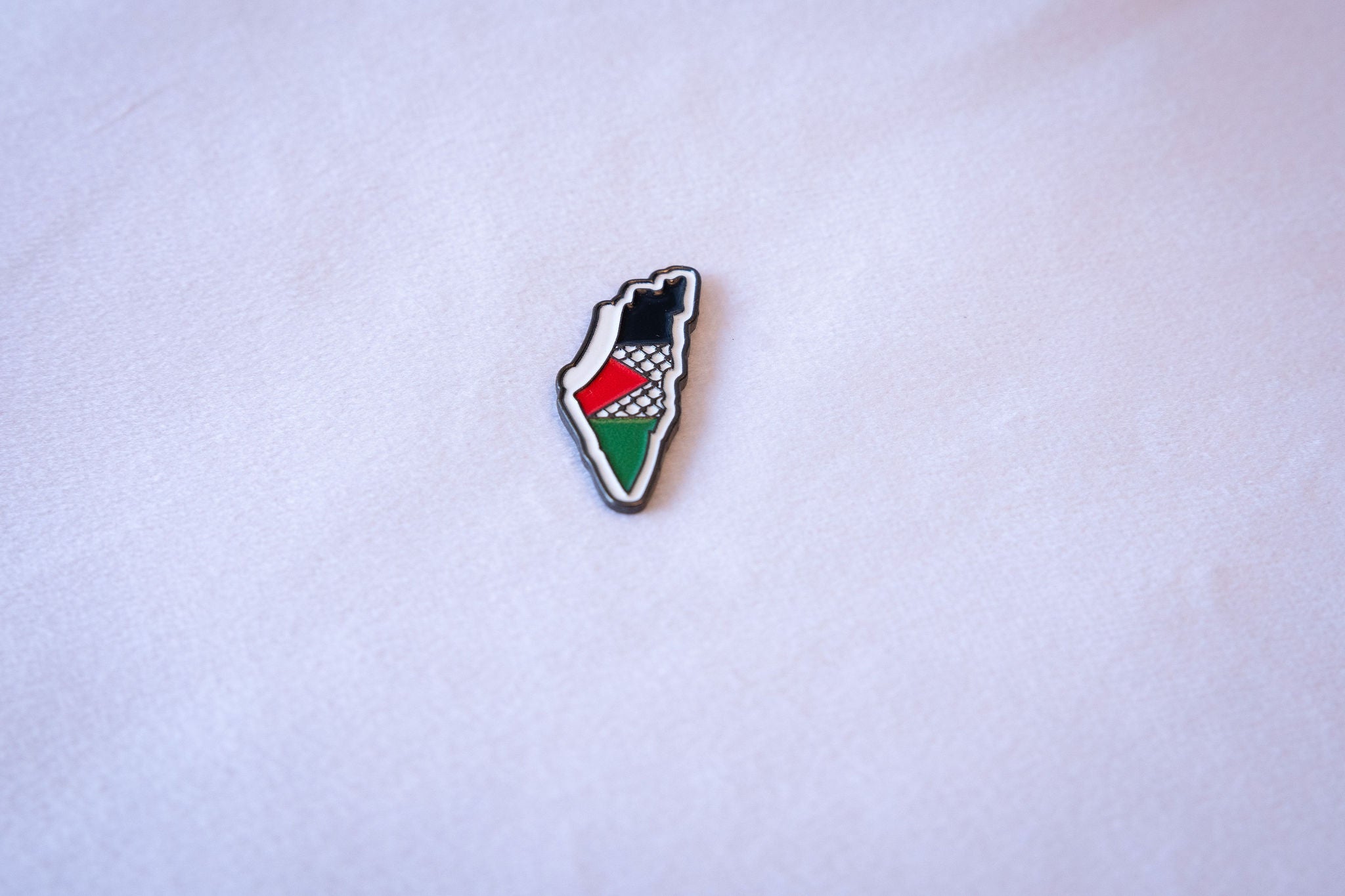 Palestine-map-shaped enamel pin in flag-color horizontal bands with keffiyeh texture