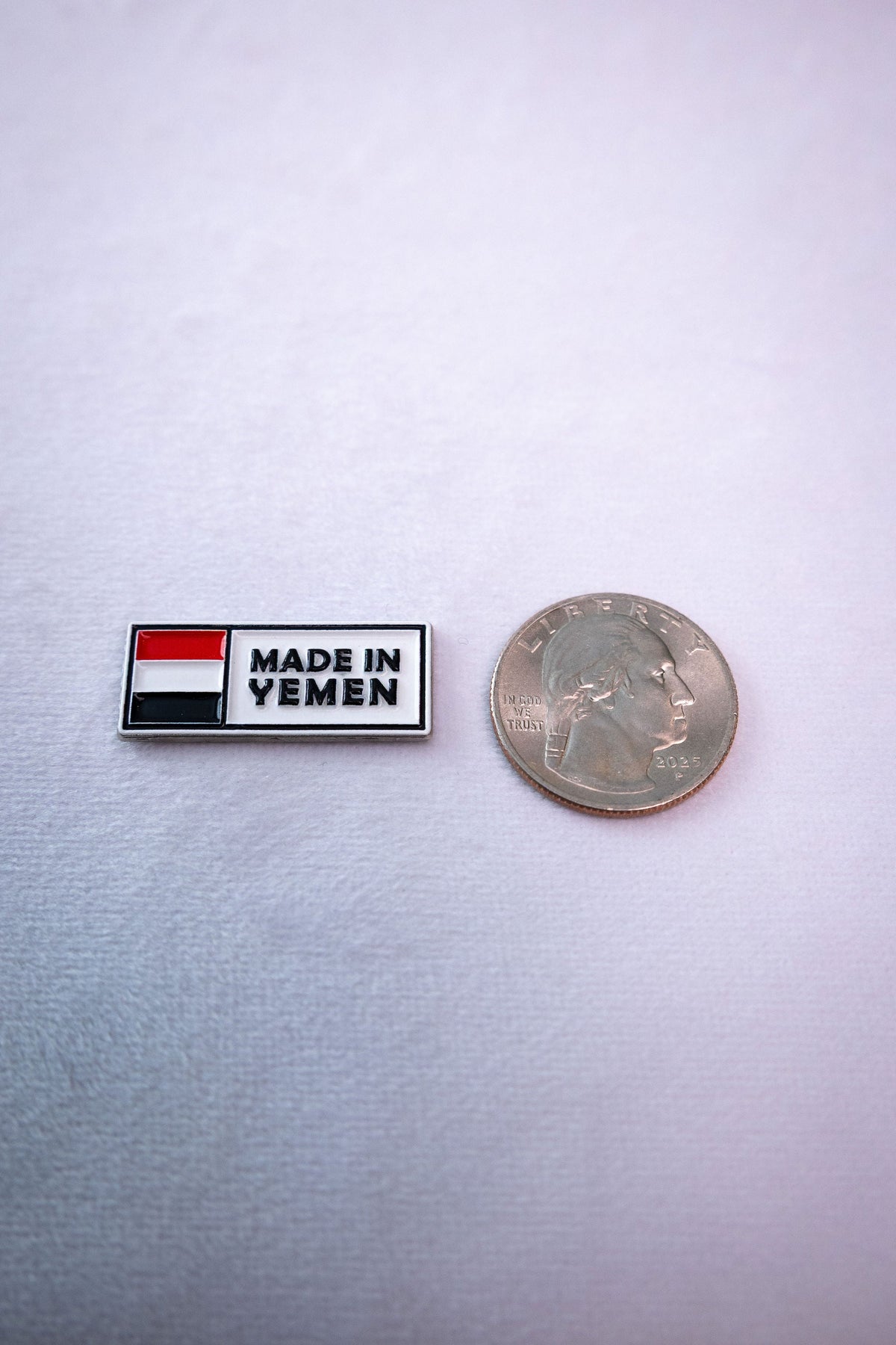 The Made in Yemen flag tag sticker beside a US quarter for scale.
