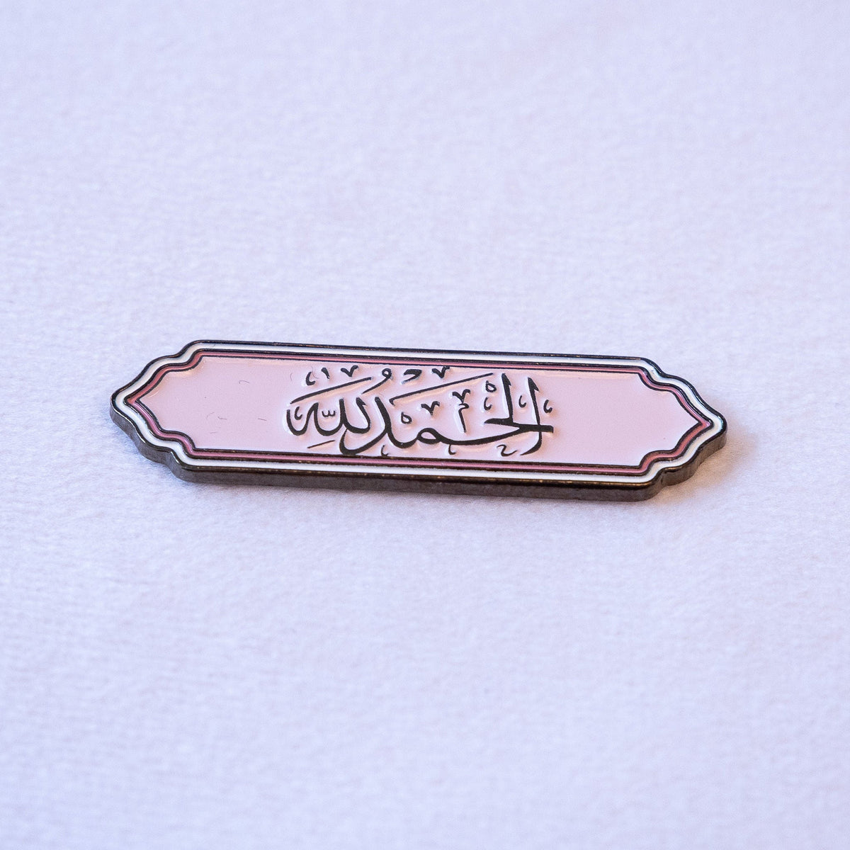 الحمد لله in black calligraphy on soft pink, in a scalloped label border with a thin pink pinstripe.