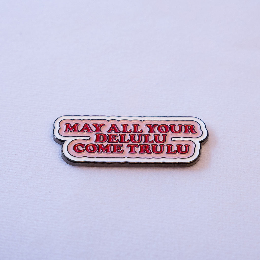 MAY ALL YOUR DELULU COME TRULU in bold red serif on a soft pink scalloped speech bubble.