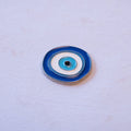 A blue and white evil eye, round, in metal.