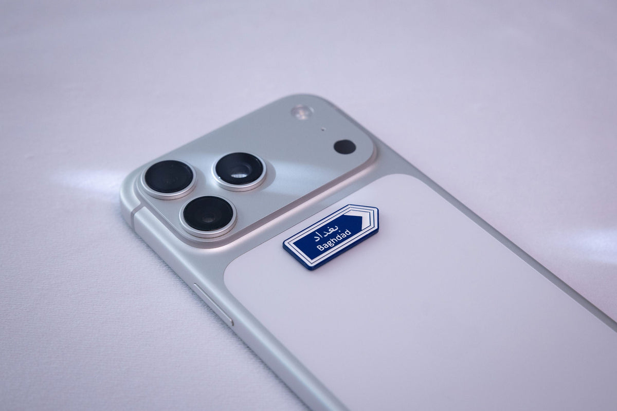 Blue Baghdad (بغداد) road-sign metal sticker, applied to a phone case near the camera bump