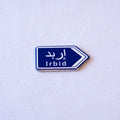 A blue highway sign cut as an arrow, إربد above Irbid.