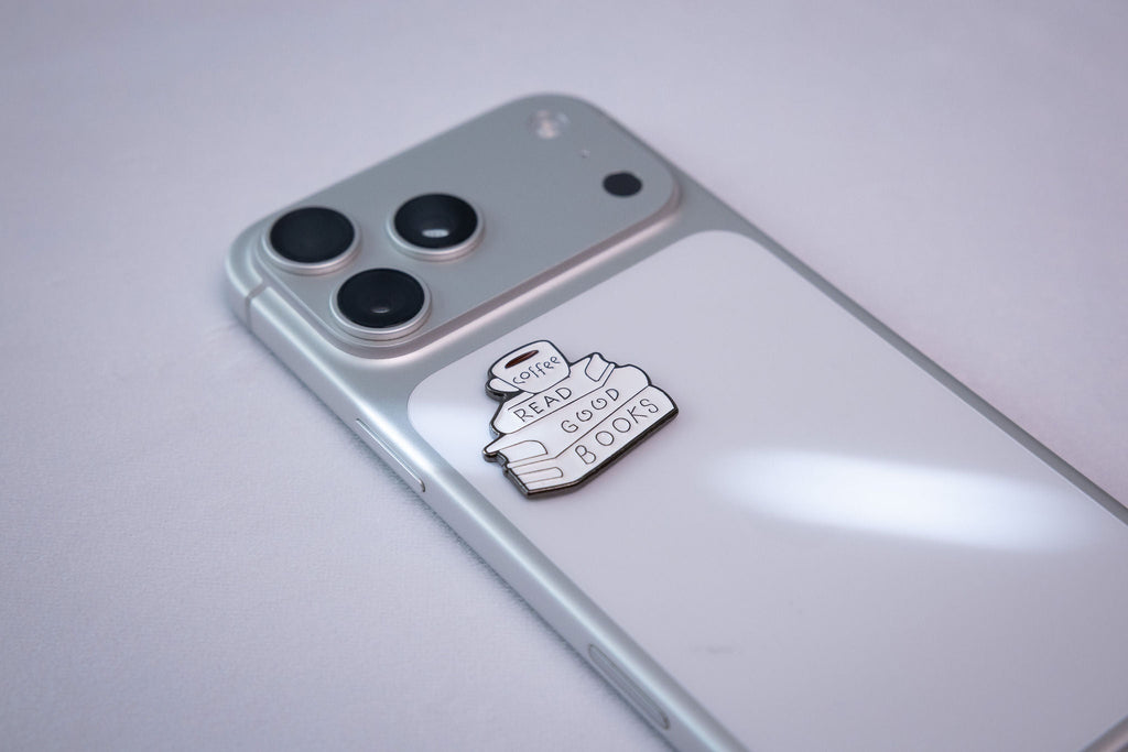 The READ GOOD BOOKS metal sticker applied to a phone case near the camera bump.