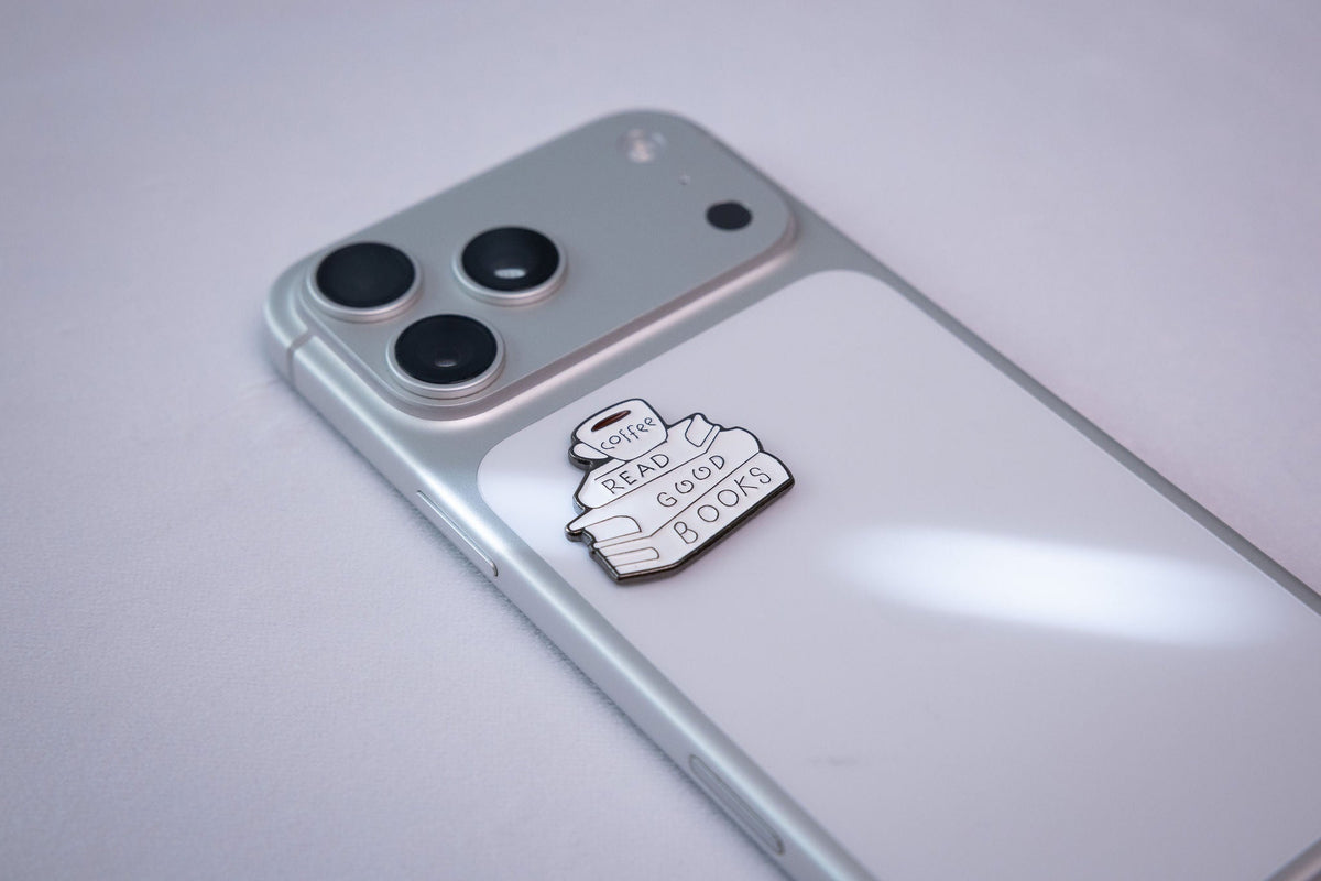 The READ GOOD BOOKS metal sticker applied to a phone case near the camera bump.