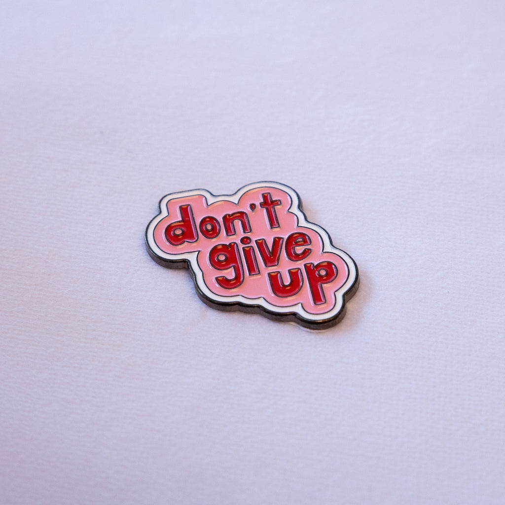 don't give up in red bubble letters on a pink cloud shape with a white outline, as a metal sticker.