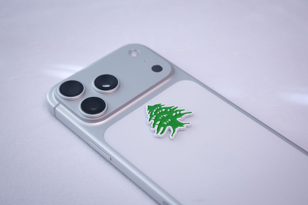 The Lebanon cedar metal sticker applied to a phone case near the camera bump.