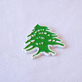The green cedar of Lebanon, die-cut to the tree's silhouette with a white outline, as a metal sticker.