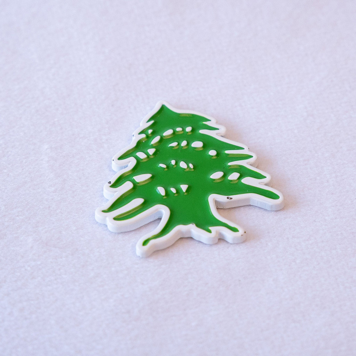 The green cedar of Lebanon, die-cut to the tree's silhouette with a white outline, as a metal sticker.
