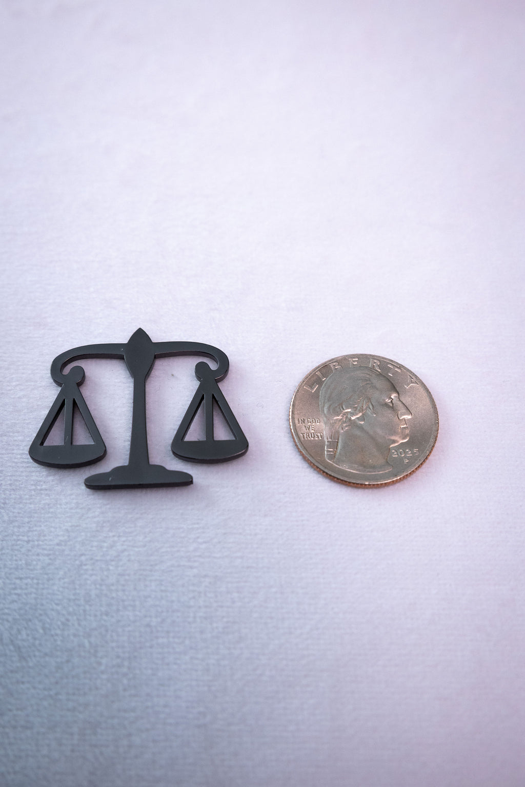 The Scales of Justice sticker beside a US quarter for scale.