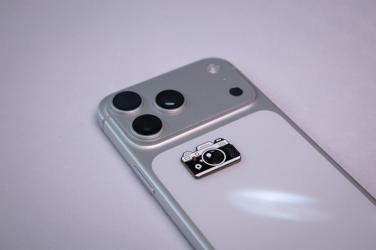 The retro camera metal sticker applied to a phone case near the camera bump.