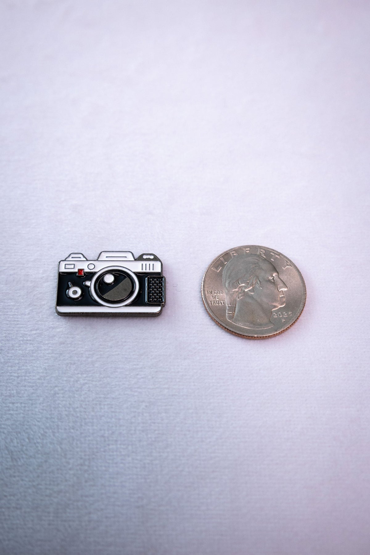 The retro camera metal sticker beside a US quarter for scale.