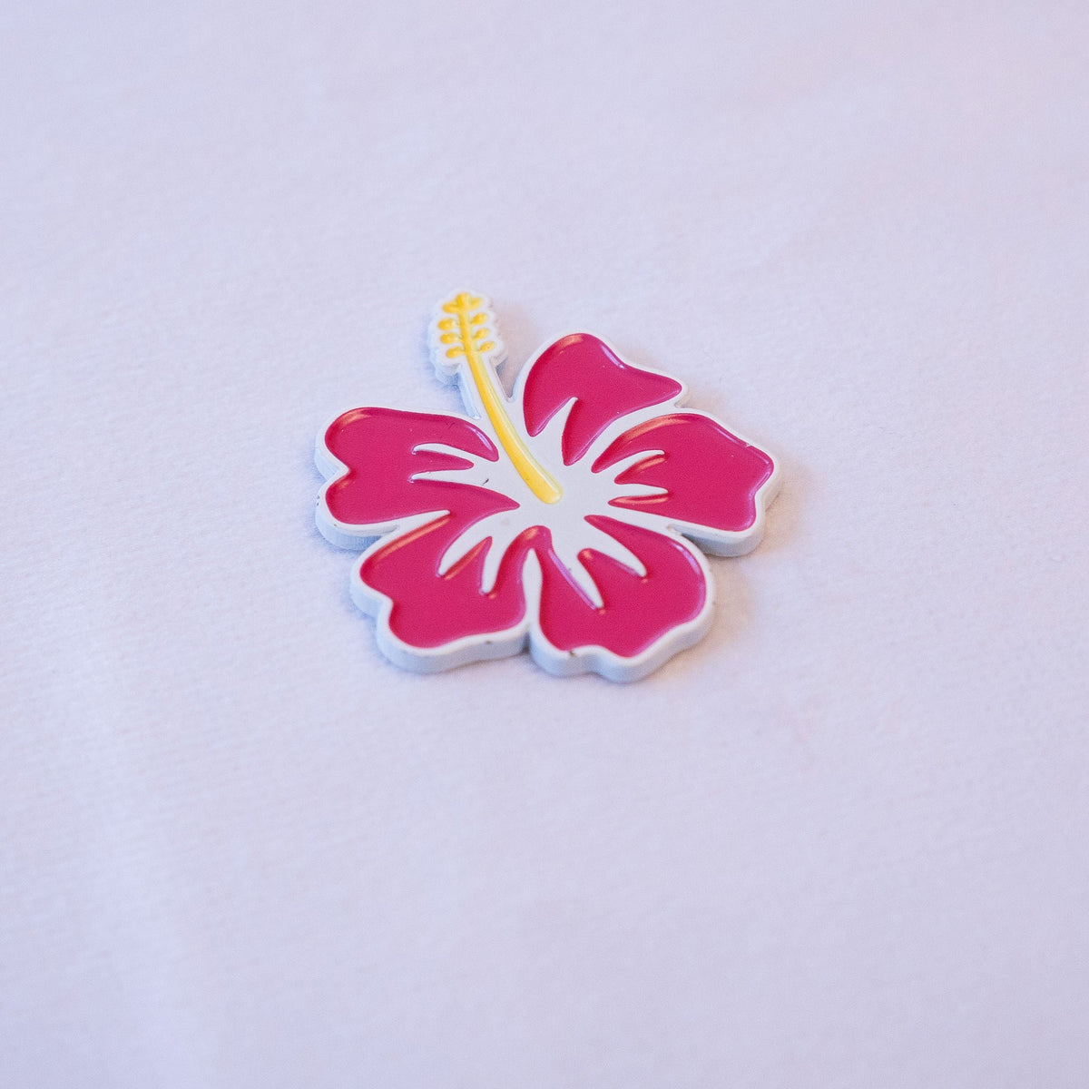 A magenta hibiscus in full bloom with a yellow stamen and a white outline, as a metal sticker.