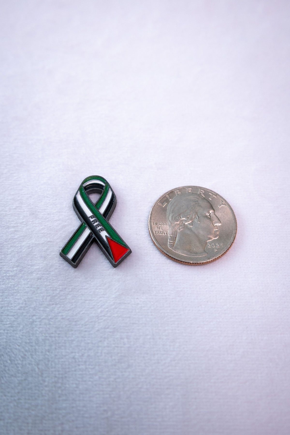 The Palestine awareness ribbon metal sticker beside a US quarter for scale.