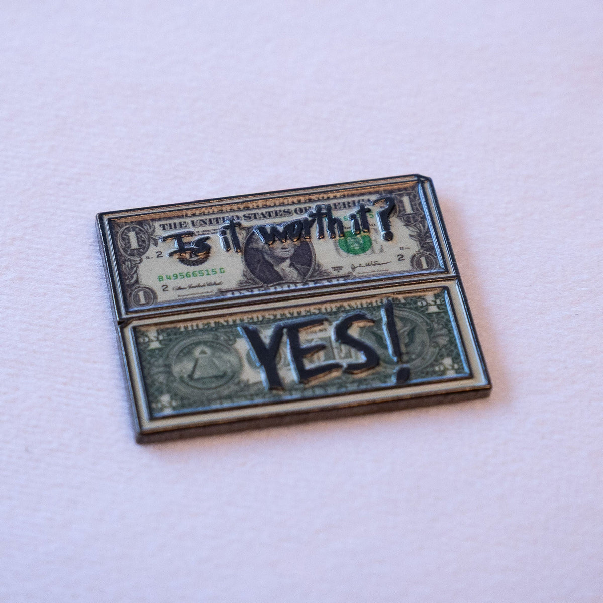 Two folded dollar bills stacked, "Is it worth it?" on the upper bill and "YES!" in bold caps across the lower one, as a metal sticker.